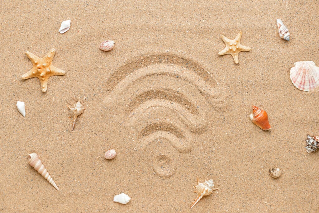 Wi-Fi symbol drawn in beach sand, surrounded by seashells and starfish