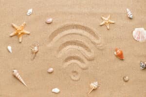 Wi-Fi symbol drawn in beach sand, surrounded by seashells and starfish